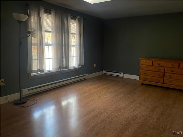 empty room featuring wood-type flooring and a baseboard radiator