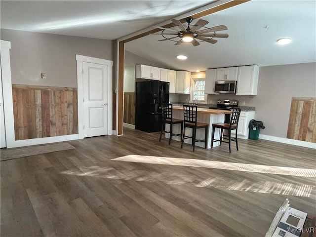 kitchen with dark hardwood / wood-style flooring, black fridge, a breakfast bar, lofted ceiling with beams, and white cabinetry