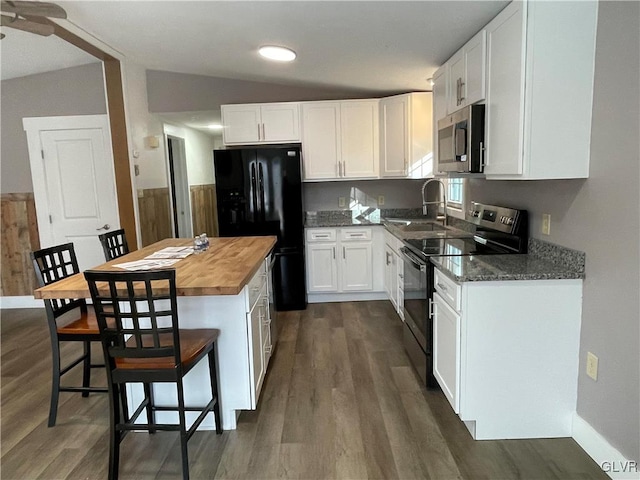 kitchen featuring black appliances, vaulted ceiling, dark hardwood / wood-style floors, butcher block countertops, and white cabinetry