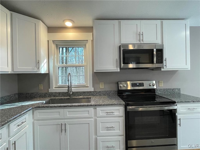 kitchen featuring white cabinets, dark stone countertops, sink, and stainless steel appliances