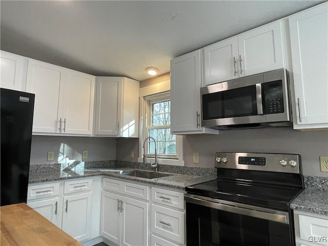 kitchen featuring white cabinets, dark stone countertops, sink, and appliances with stainless steel finishes