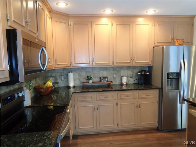 kitchen with appliances with stainless steel finishes, dark stone countertops, and dark wood-type flooring