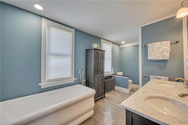 bathroom featuring a tub to relax in, vanity, radiator heating unit, and toilet