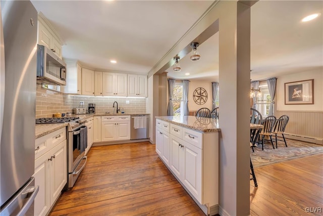 kitchen with light hardwood / wood-style flooring, sink, stainless steel appliances, light stone countertops, and white cabinetry