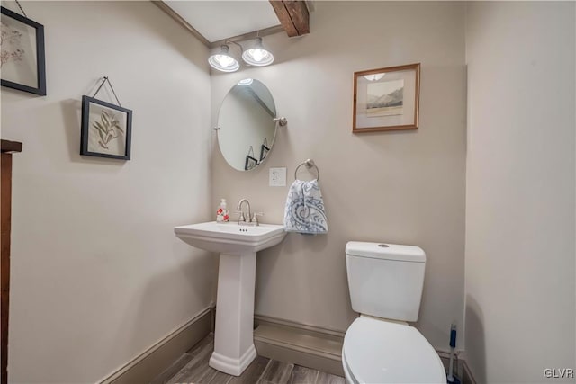 bathroom featuring wood-type flooring, beam ceiling, and toilet