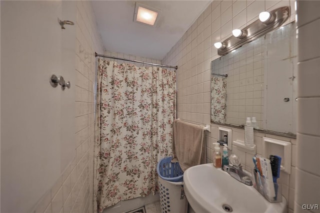 bathroom with tile patterned flooring, curtained shower, sink, and tile walls