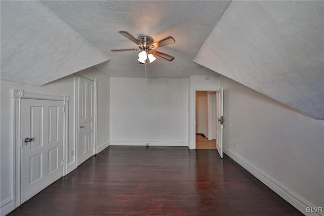 bonus room featuring lofted ceiling, ceiling fan, dark wood-type flooring, and a textured ceiling