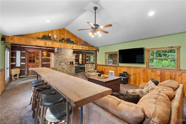 living room with lofted ceiling, carpet flooring, wooden walls, and ceiling fan