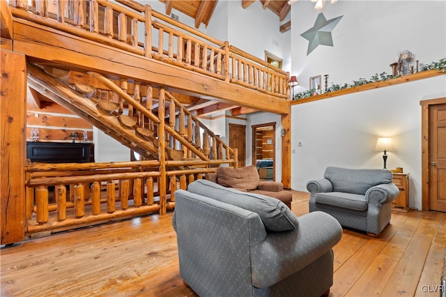 living room featuring beamed ceiling, light wood-type flooring, and a towering ceiling