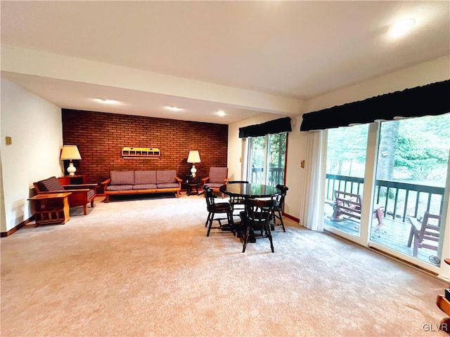 dining space featuring brick wall and light colored carpet