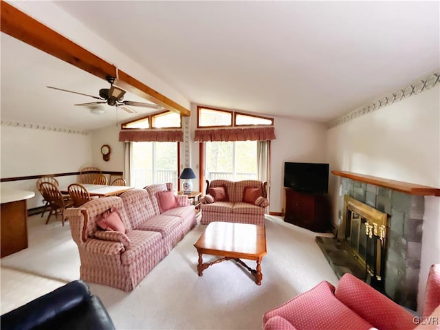 living room with ceiling fan, a stone fireplace, lofted ceiling with beams, and carpet