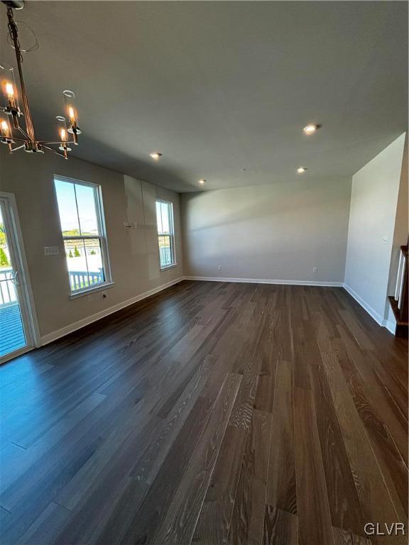 unfurnished room with an inviting chandelier and dark hardwood / wood-style flooring