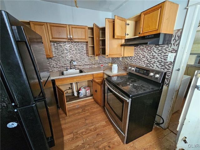 kitchen with decorative backsplash, black refrigerator, sink, electric stove, and light hardwood / wood-style flooring