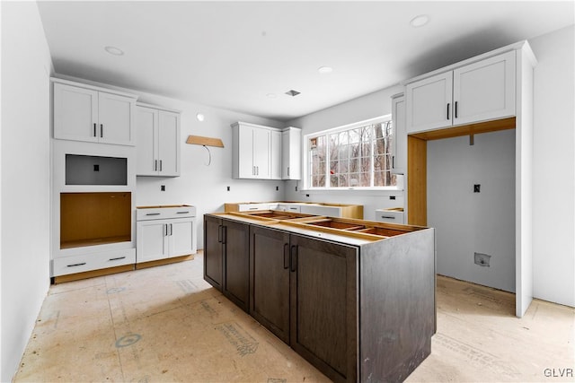 kitchen with white cabinetry, dark brown cabinets, and a center island