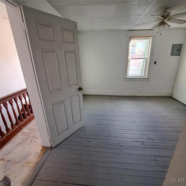 empty room with a paneled ceiling, ceiling fan, electric panel, and light hardwood / wood-style floors