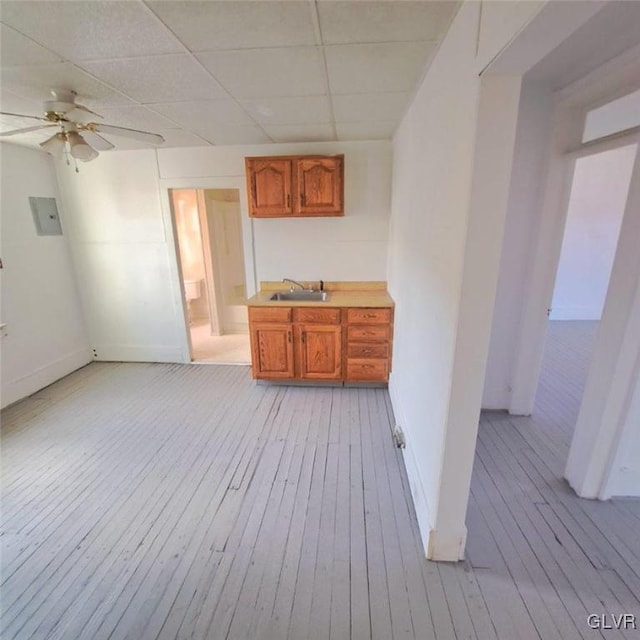 interior space featuring a paneled ceiling, ceiling fan, light wood-type flooring, and sink