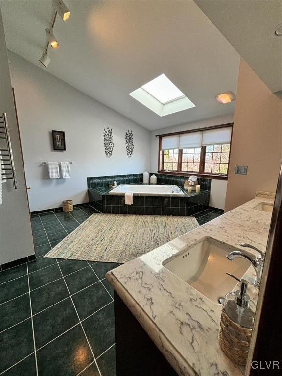 bathroom with vanity, tile patterned flooring, a relaxing tiled tub, and vaulted ceiling with skylight