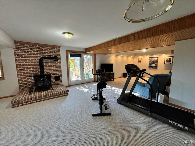 workout area with a wood stove, french doors, and carpet