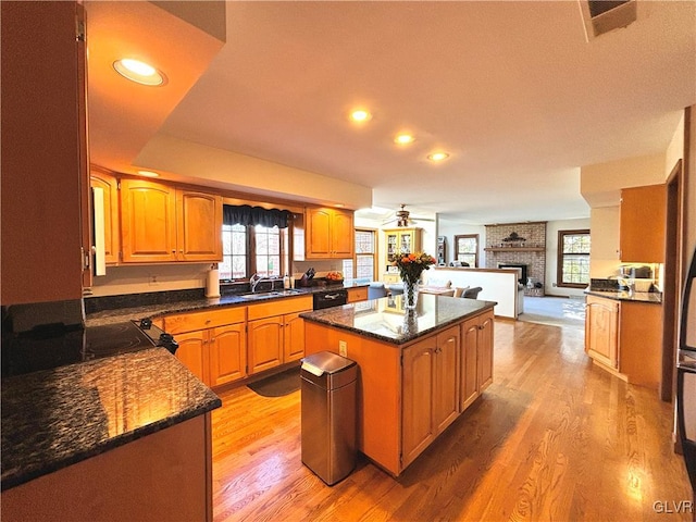 kitchen with a center island, sink, a brick fireplace, light hardwood / wood-style flooring, and ceiling fan