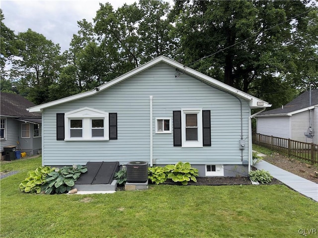 rear view of property with cooling unit and a lawn