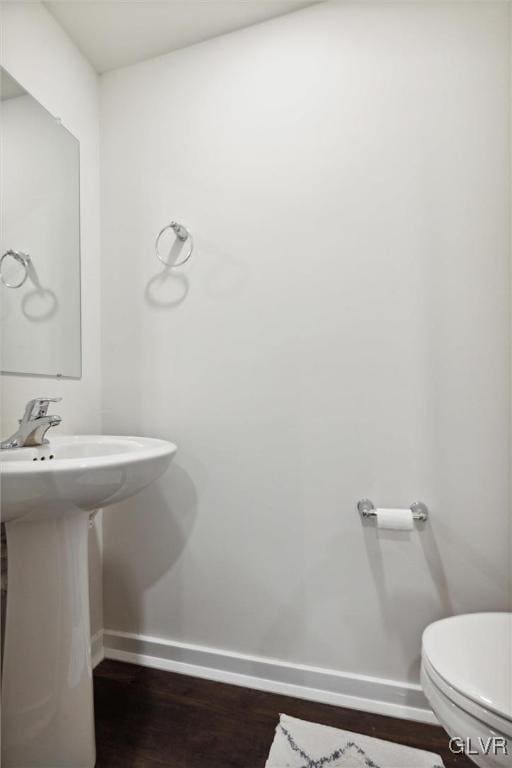 bathroom featuring toilet, wood-type flooring, and sink