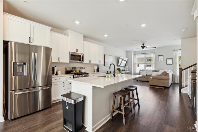 kitchen with a kitchen island with sink, white cabinets, sink, ceiling fan, and appliances with stainless steel finishes