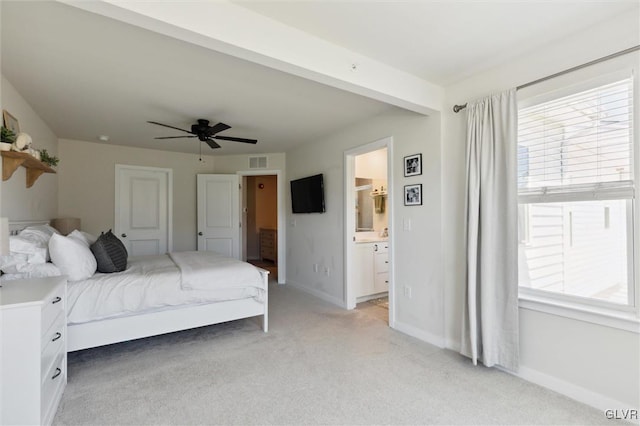 bedroom featuring ceiling fan, light colored carpet, connected bathroom, and multiple windows