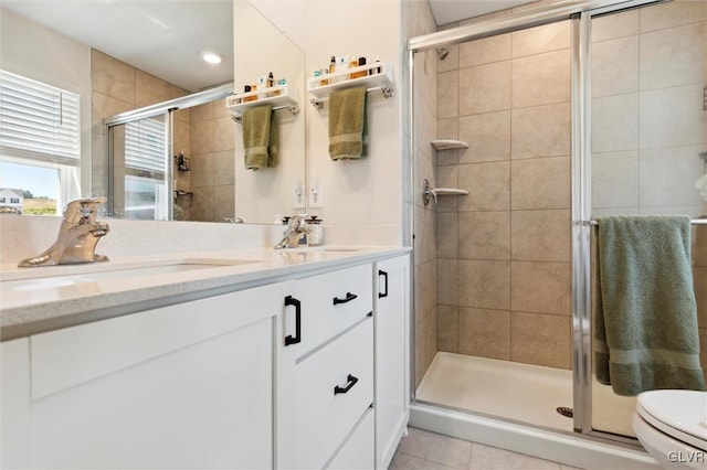 bathroom with tile patterned floors, a shower with door, vanity, and toilet