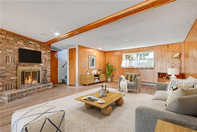 living room featuring light hardwood / wood-style flooring, wood walls, a baseboard heating unit, and a brick fireplace