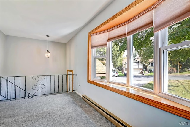 spare room featuring a baseboard heating unit, a wealth of natural light, and carpet floors