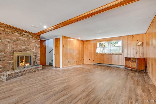 unfurnished living room featuring light hardwood / wood-style flooring, a baseboard heating unit, wooden walls, and a brick fireplace