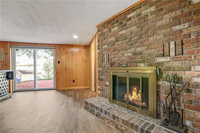 unfurnished living room with hardwood / wood-style floors, wooden walls, and a brick fireplace