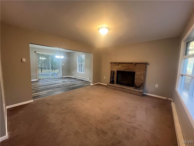 unfurnished living room with baseboard heating, dark colored carpet, and a fireplace