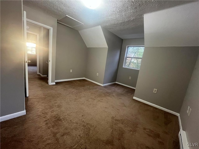 bonus room featuring a textured ceiling, lofted ceiling, baseboard heating, and dark carpet