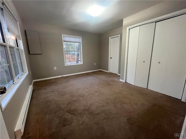 unfurnished bedroom featuring a closet, a baseboard heating unit, and dark colored carpet