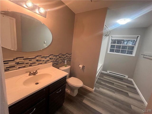 bathroom with hardwood / wood-style floors, toilet, baseboard heating, vanity, and decorative backsplash