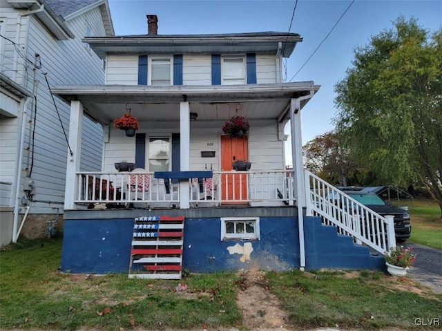 view of front of house with covered porch and a front lawn