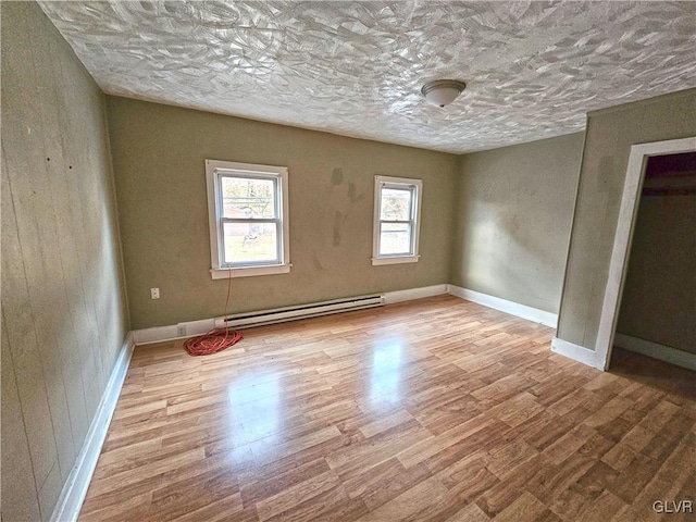 empty room featuring light wood-type flooring and a baseboard radiator