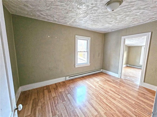 unfurnished room featuring light wood-type flooring and a baseboard heating unit