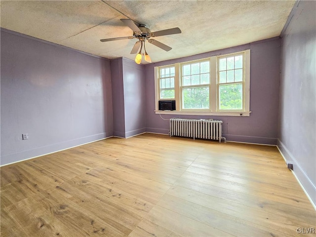 spare room featuring a textured ceiling, radiator heating unit, light wood-type flooring, and ceiling fan