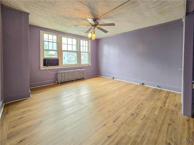 spare room with a textured ceiling, radiator, light wood-type flooring, and ceiling fan