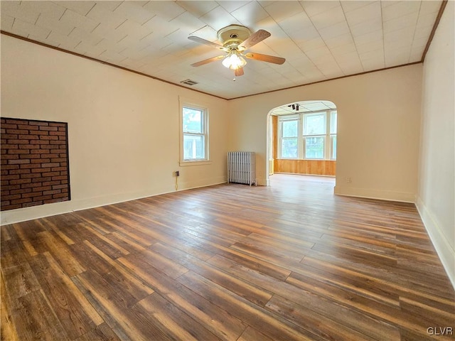 empty room featuring ceiling fan, radiator heating unit, dark hardwood / wood-style floors, and plenty of natural light