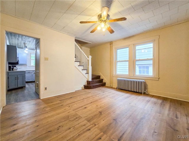 spare room with ceiling fan, wood-type flooring, and radiator