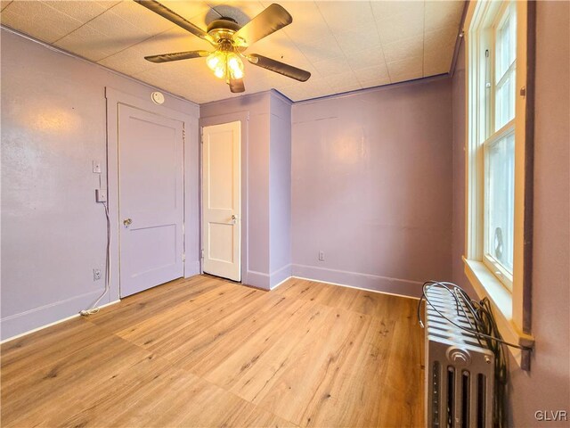 spare room with radiator, ceiling fan, and light hardwood / wood-style flooring