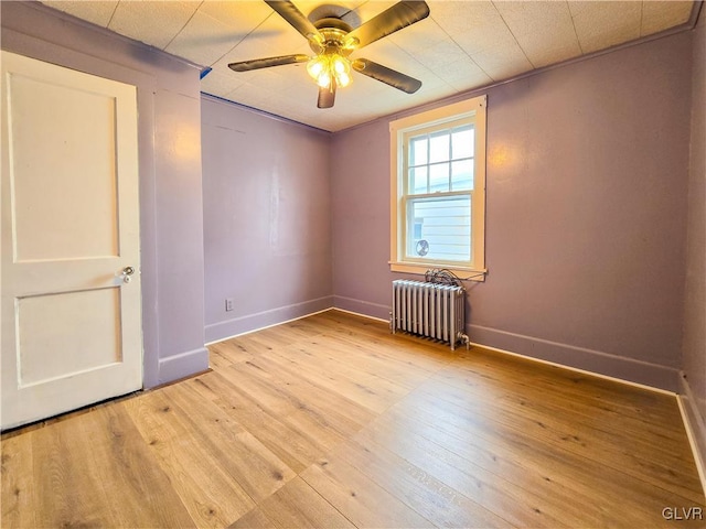 unfurnished room featuring light hardwood / wood-style flooring, ceiling fan, and radiator