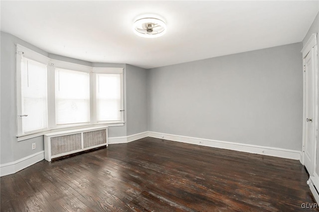 spare room with hardwood / wood-style floors, radiator heating unit, and a healthy amount of sunlight