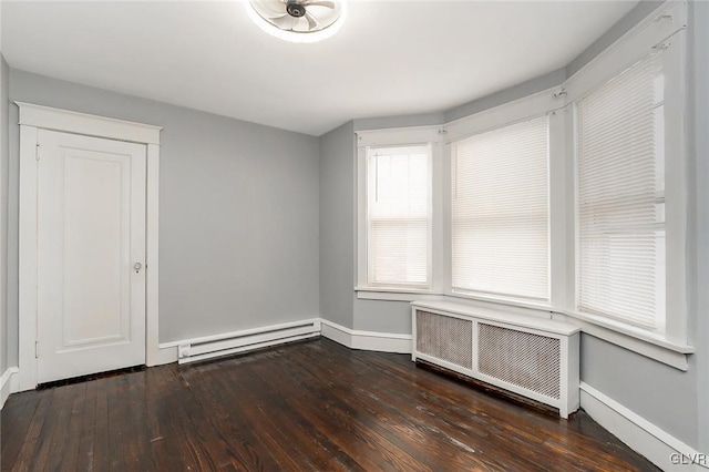 empty room featuring a baseboard heating unit, radiator heating unit, and dark hardwood / wood-style floors