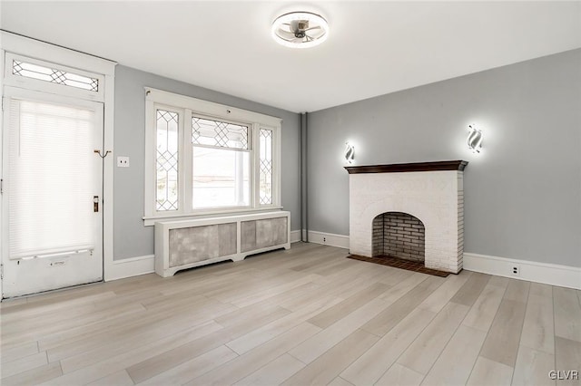 unfurnished living room with a fireplace, radiator, and light hardwood / wood-style flooring