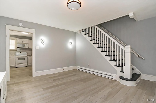 stairway with hardwood / wood-style floors and baseboard heating