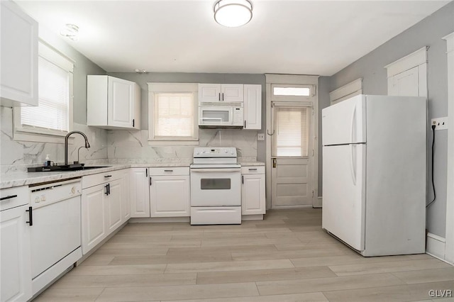 kitchen with white appliances, a healthy amount of sunlight, white cabinetry, and tasteful backsplash